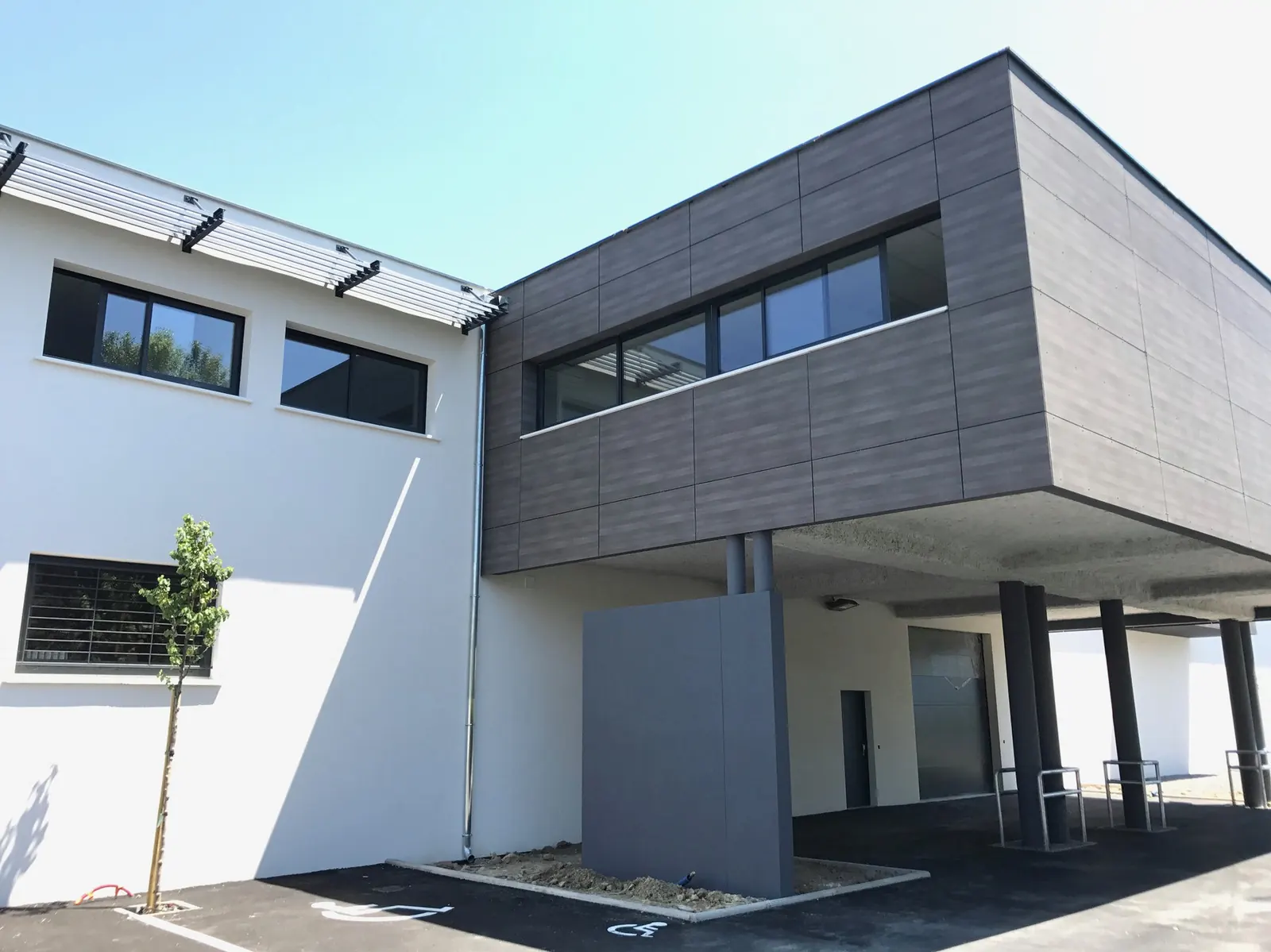 Siège social O — Un siège d'entreprise aux volumes affirmés, habillé de panneaux minéraux sombres.
